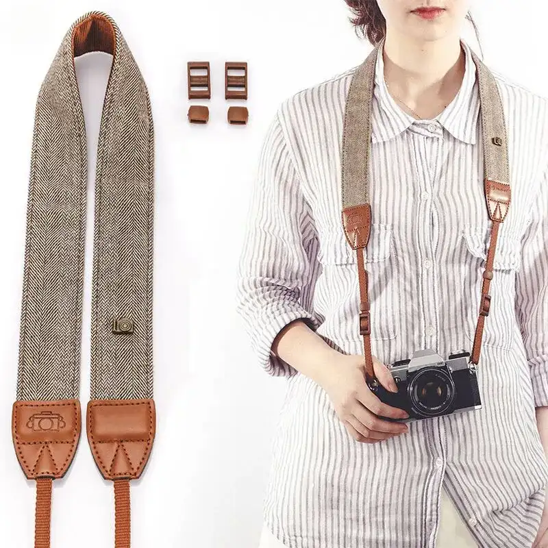 The Camel cotton and leather strap laid flat next to a photographer wearing the same strap around her neck, camera resting at chest height